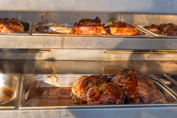 Succulent meats sizzling in golden trays at a vibrant outdoor grill festival in the warm afternoon sun