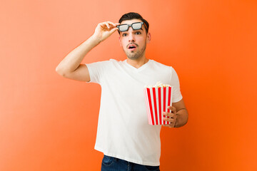 Man reacting to exciting movie while holding popcorn and wearing 3d glasses for entertainment