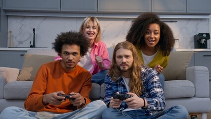 Multiethnic African Caucasian friends men women playing console video game at home competition fun win lose diverse four group males females buddies friendship support gaming joy entertainment indoors