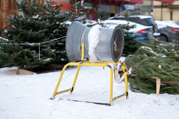 Christmas tree netting machine at an outdoor winter market with snow-covered firs