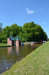 A lock on the Elbląg Canal surrounded by greenery.,