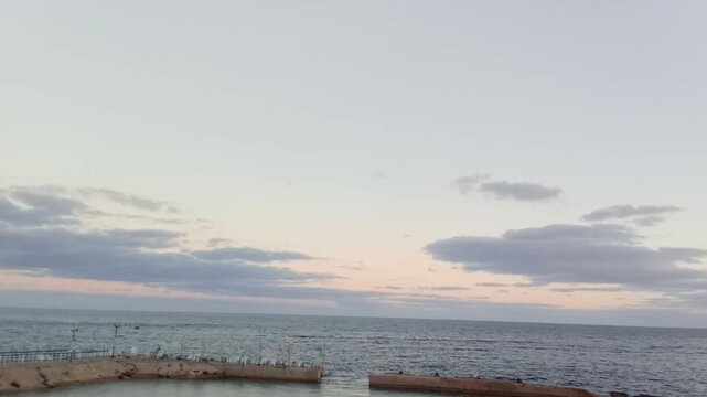 A great view of the Mediterranean Sea and the sky is next to Bridge 45. The view is near the sunrise. The bridge is on the Corniche Road in Alexandria, Egypt. It has a pedestrian walkway.