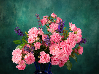A bouquet of Mossroses in a blue vase with lavender against a dark green background.
