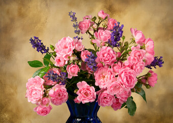 A bouquet of Mossroses in a blue vase with lavender against a honey colored background.