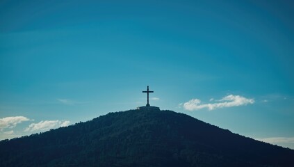 Large cross atop a hill with a bright sky, functioning as a navigation aid in the cityscape, World Heritage Day