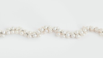 Obraz premium White pearl necklace laid flat on a neutral surface, used for catalog or online shop listings, jewelry photography