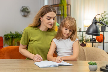 Mother and daughter at home check math answer use notebook and pen mark ticks say hooray feel proud. Woman and girl at table explain steps count sums check work learn rule practice focus steady pace
