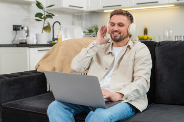 Young man at home works on laptop as calm music plays and focus rises with a steady pace. Caucasian guy on sofa types with relaxed mood keeps rhythm and focus and finishes tasks with quiet joy at end.