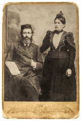 Portrait of a Jewish family from 1890-1910. A bearded man in a formal suit and vest, sitting next to a standing woman in a dress.