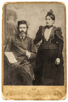 Portrait of a Jewish family from 1890-1910. A bearded man in a formal suit and vest, sitting next to a standing woman in a dress.