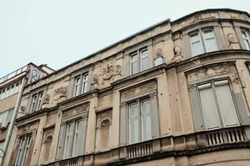 Obraz premium Ornate historic building facade with carved details and tall windows in morning Sarajevo. Decorative architecture highlights European urban heritage.