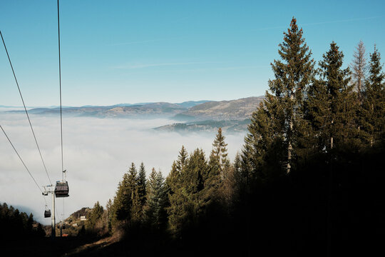 Cable car rising above a sea of clouds on Trebevic mountain in Bosnia and Herzegovina. Scenic alpine view shows tourism infrastructure, elevation, winter atmosphere, and peaceful mountain travel.