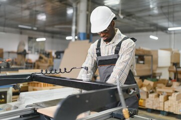 Carpenter using woodworking machine in furniture factory