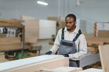 Carpenter moving wooden panels in furniture factory