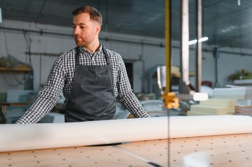 Carpenter unrolling white fabric roll in furniture factory