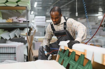 African american Furniture maker assembling sofa in factory
