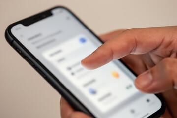 Hand tapping smartphone showing blurred UI mockup.