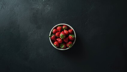 Bright red strawberries arranged on a dark countertop, suitable for culinary styling backgrounds