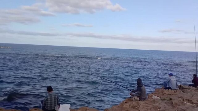 For fishing, fishermen are sitting on a rock opposite Masoud Well. A great view of the Mediterranean Sea and the sky is opposite the fishermen in the morning. It's in Sidi Bishr, Alexandria, Egypt.