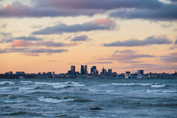 Naklejka premium Tallinn city skyline and modern skyscrapers during a dramatic winter storm with powerful waves on the Baltic Sea in Estonia.