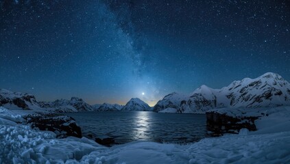 Night scene of starry sky and Milky Way over icy coastline and snow-capped peaks in winter in Arctic region for astrophotography