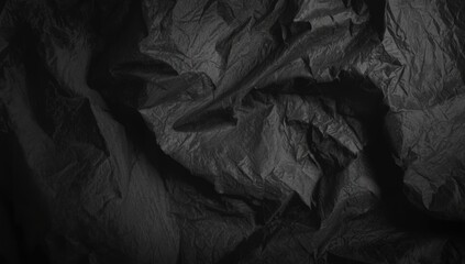 Textured dark fabric with deep creases and shadow play, used as backdrop for layouts or textiles