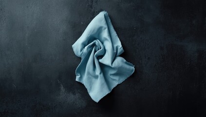 Blue pastel linen napkin placed on dark textured surface, serving as a background for editorial use, Earth Day