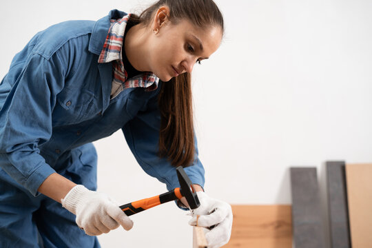 woman using a hammer to assembly furniture working at home interior