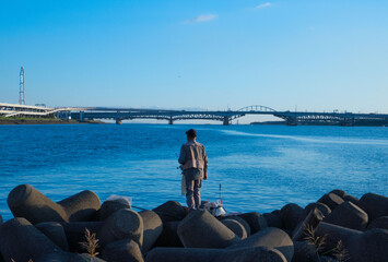 堤防で釣りをする老人、テトラポットの上での釣り