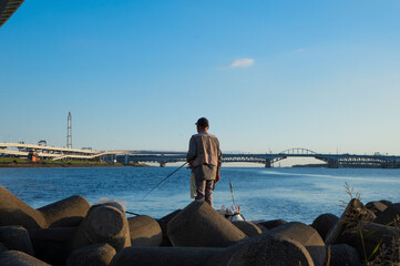 堤防で釣りをする老人、テトラポットの上での釣り