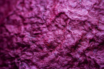 Extreme close up of purple handmade paper clay with a structure and rough texture. Paper recycling. Selective soft focus, shallow depth of field.