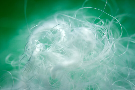 Extreme macro of polyester stable fiber on green background. Selective focus, shallow depth of field. Abstract dreamy background