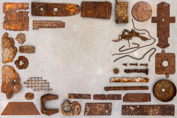 A group of various old rusty bits and pieces arranged on a concrete surface. Old rusty nuts, bolts, nails and other parts flay lay on gray background.