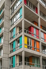 Fototapeta premium Colorful balcony shutters contrast with the brutalist architecture of a concrete building