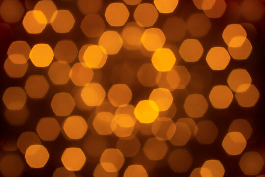 Abstract soft-focus background with warm golden hexagon bokeh lights, creating a cozy and elegant atmosphere ideal for festive, holiday, luxury, or romantic designs.