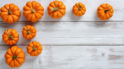 A group of small orange pumpkins sits on a white wooden surface. They are arranged in a casual way showing the colors of autumn. This setting is suitable for fall decoration.