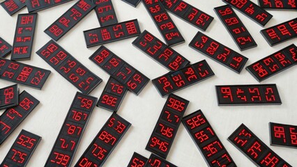 A collection of digital displays showing various numbers in red on black backgrounds, scattered across a light surface.
