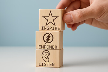 Leadership concept. Hand stacking blocks labeled Inspire, Empower, and Listen. Symbolic representation of strategic growth, branding identity, emotional intelligence, and team-building innovation.