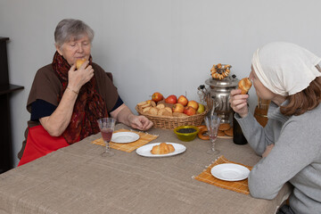 elderly woman and a guest eating croissants at the table. Concept of a relative visiting an elderly person. Elderly care and support.