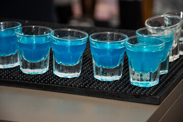  several shots of a Blue Kamikaze cocktail. 
This drink is a variation of the classic Kamikaze cocktail, which typically consists of equal parts vodka, triple sec, and lime juice. 