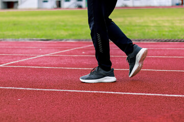 Runner feet on red track with white lines, athletic shoes, outdoor stadium, fitness concept