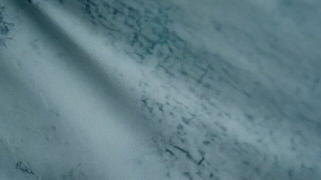 Detailed macro slow motion shot of white cotton fabric with blue abstract marble liquid ink splashes and fluid art pattern texture moving smoothly