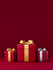 Obraz premium Three red gift boxes with gold and silver ribbons on deep red background