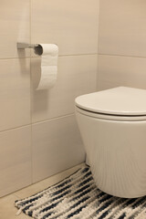 Interior of restroom with toilet bowl and carpet, tiled walls and floor.