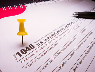 Closeup of IRS 1040 income tax form 2025 2026 marked with yellow push pin