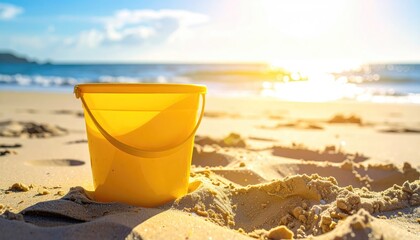 Bright Yellow Bucket on Sandy Beach Under Golden Sunlight With Ocean Waves and Blue Sky Background
