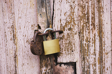 Rusty Vintage Padlock and New Brass Lock on Weathered Pink Wooden Door