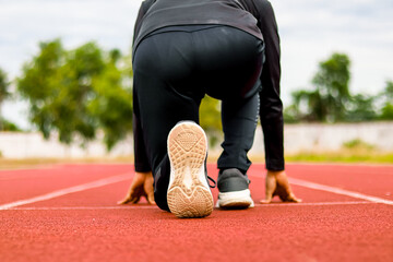 Runner poised at starting blocks on a red track, ready for race, athletic focus