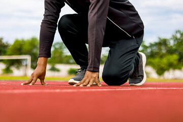 Athlete ready to start on track, close up on hands and knees