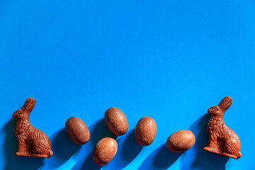 Easter chocolate bunnies and chocolate eggs on blue background. Top view